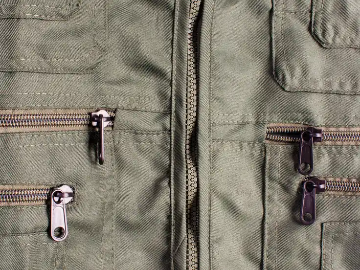 Olive jacket with metal zippers and zip pockets, details checked during final inspection