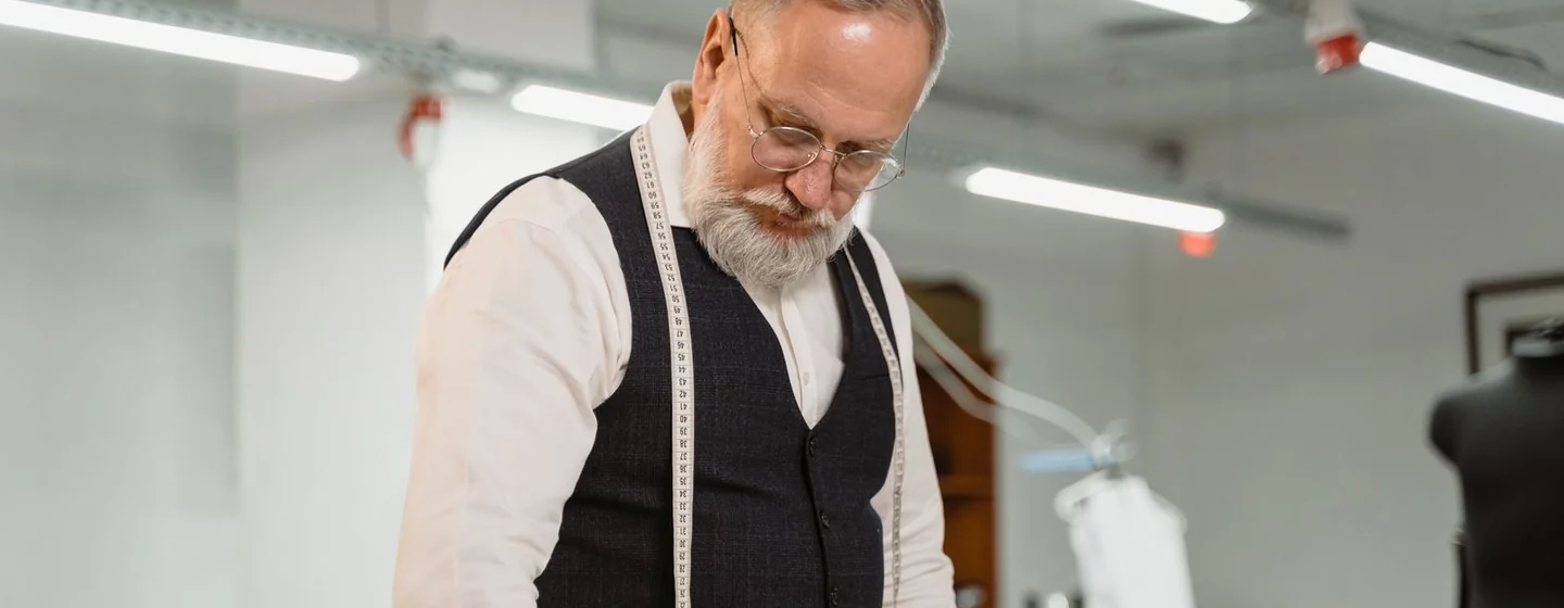 Production specialist with a tape measure checking a garment on the cutting table