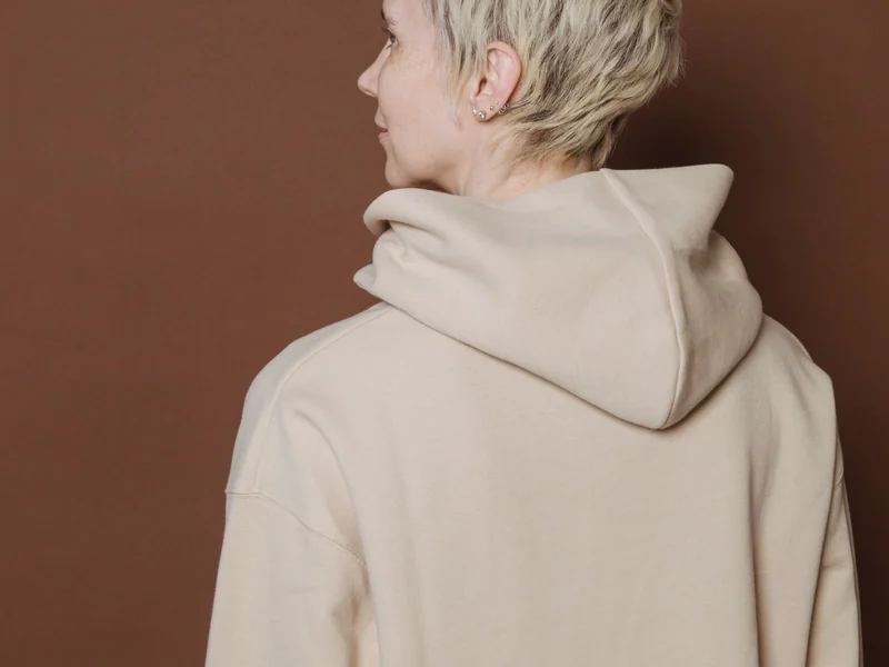 Back view of a cream oversized hoodie showing the wide body and dropped shoulder line