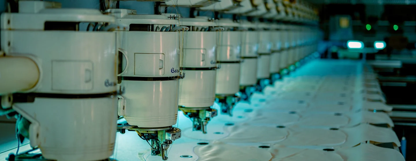 Row of industrial multi-head machines stitching panels on a production line